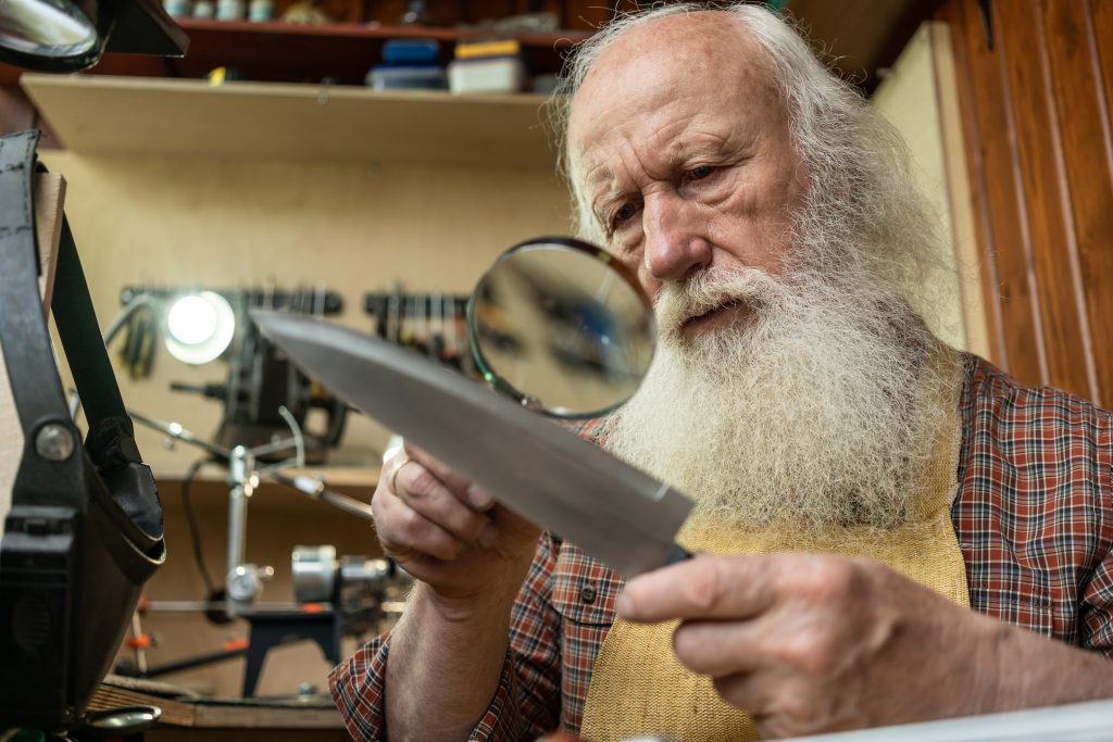 GrandDad examines a knife with a magnifying glass.